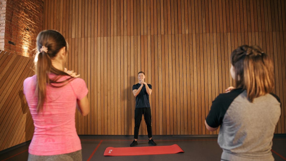 Fitness instructor leading a training session with two women in a modern gym setting.
